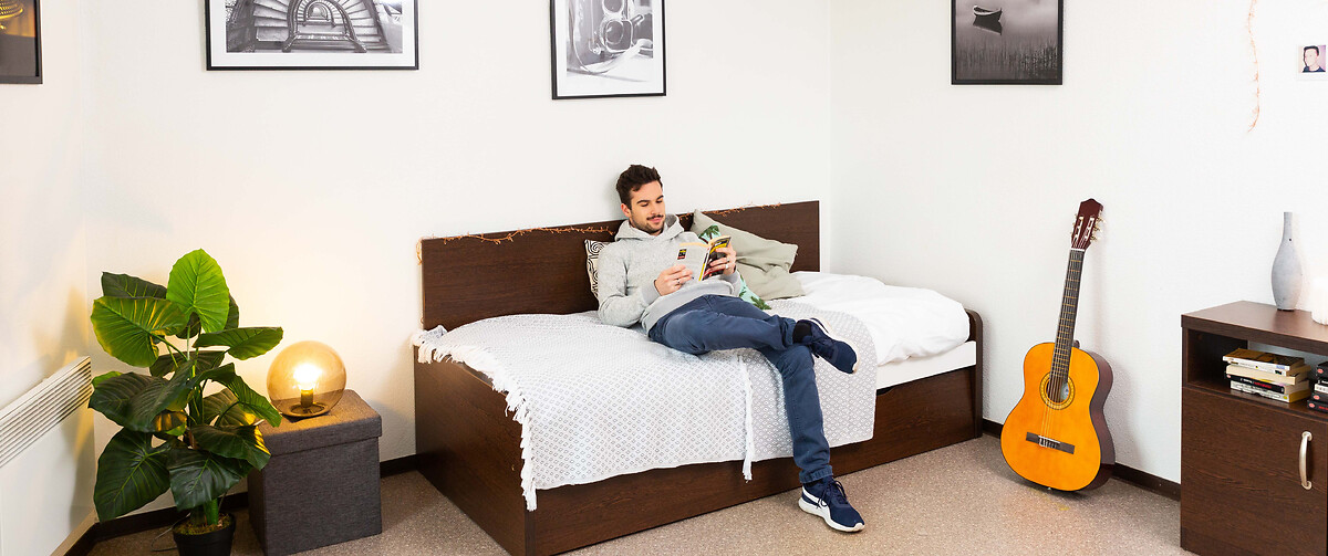Student or young professional reading a book in his accomodation for students and young professionals Talence University