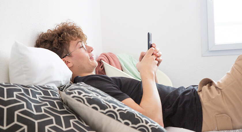Etudiant sur son lit avec son téléphone dans une résidence YouFirst Campus